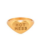 Gold heart-shaped ring with 'HOT MESS' engraving on a white background