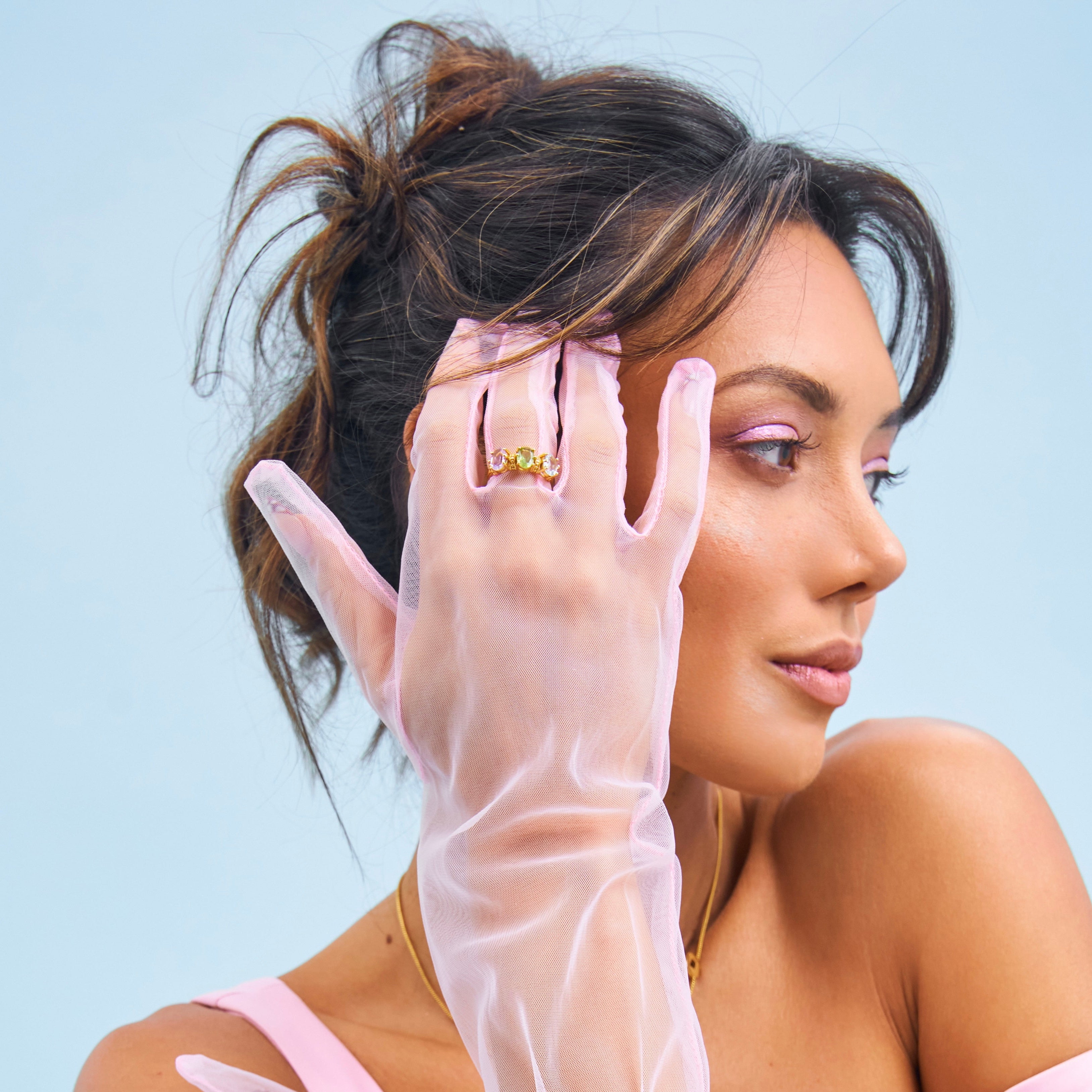 Woman wearing sheer gloves and a pink outfit against a light blue background