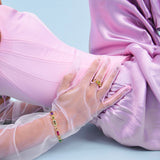 Person wearing a pink dress with sheer sleeves on a light blue background