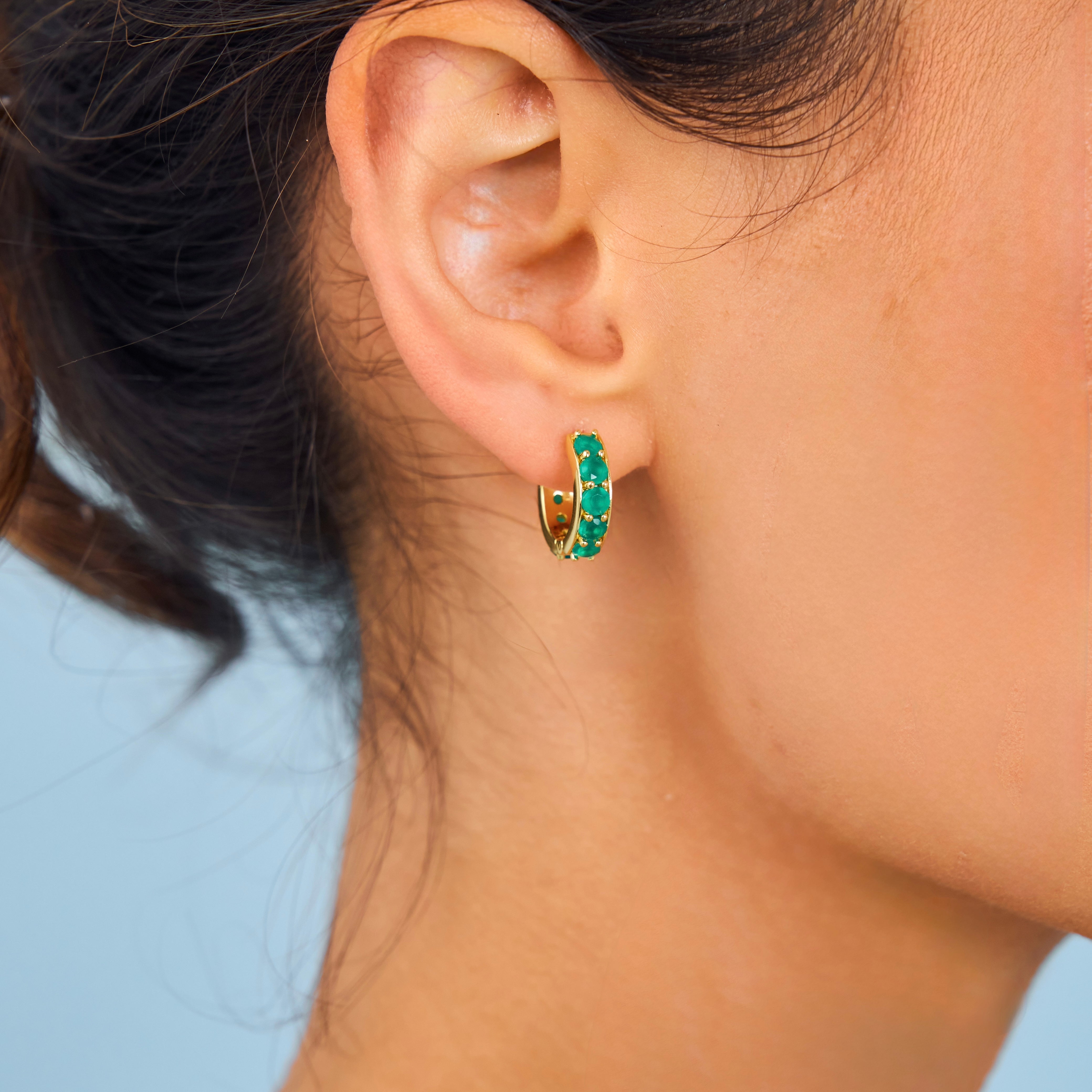 Model wearing green gemstone hoops