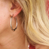 Close-up of a person wearing a silver hoop earring with blonde hair.
