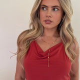 Woman wearing a red top with a necklace against a plain background