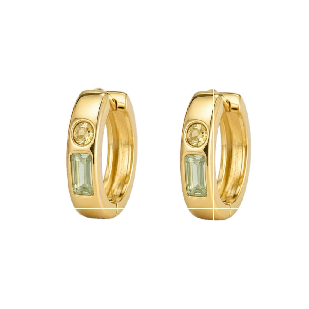 A pair of gold huggie hoop earrings, each featuring a small round clear stone and a larger rectangular light green baguette-cut stone, shown on a plain white background.
