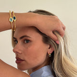 Woman wearing gold jewelry with a neutral background