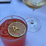 Bubble letter necklace on a glass of Aperol