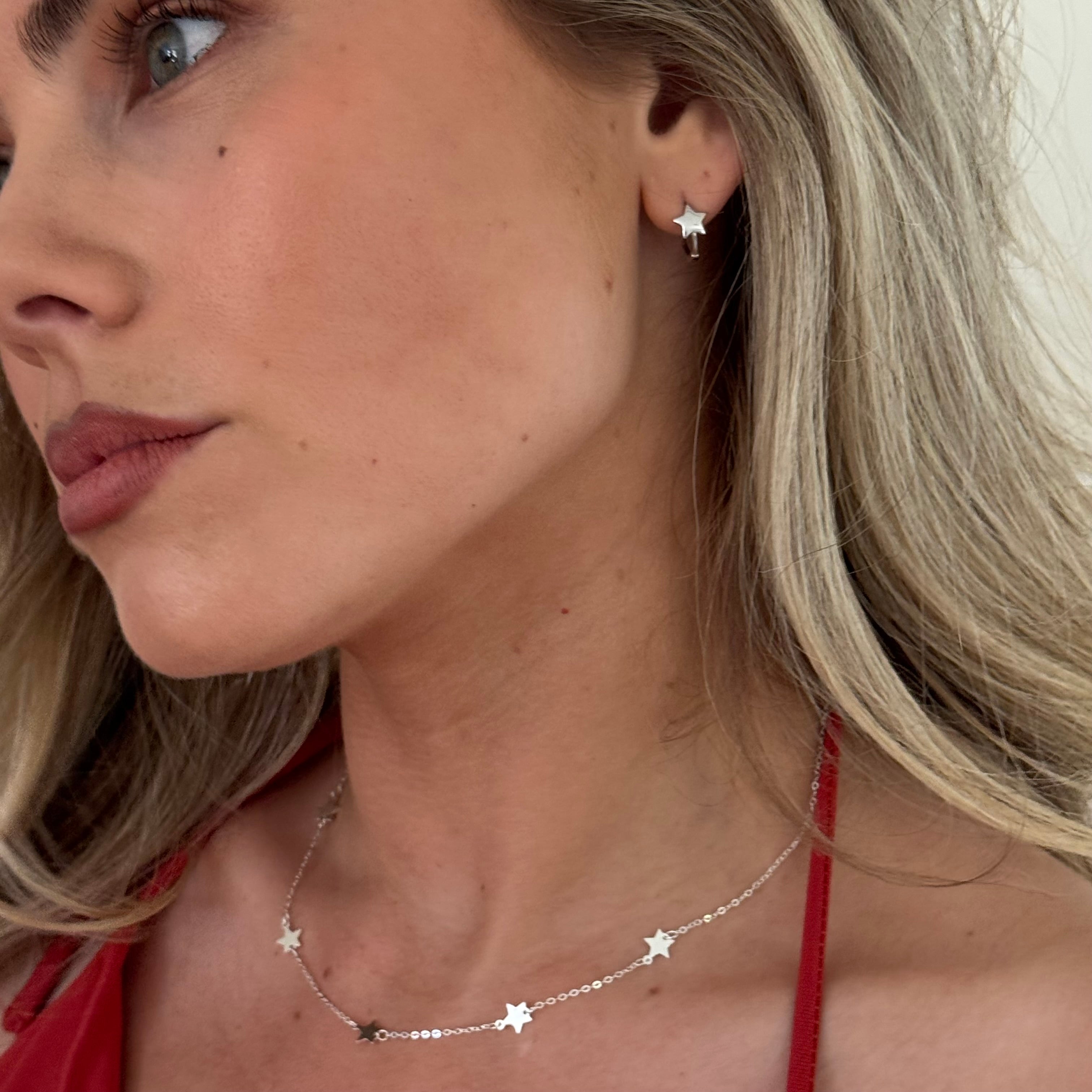 Close-up of a woman wearing star-shaped earrings and a necklace.