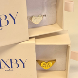 Gold ring with 'HOT MESS' on a heart-shaped band in a 'BIXBY and co' box.