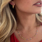 Close-up of a woman wearing a colorful beaded necklace and gold earrings.