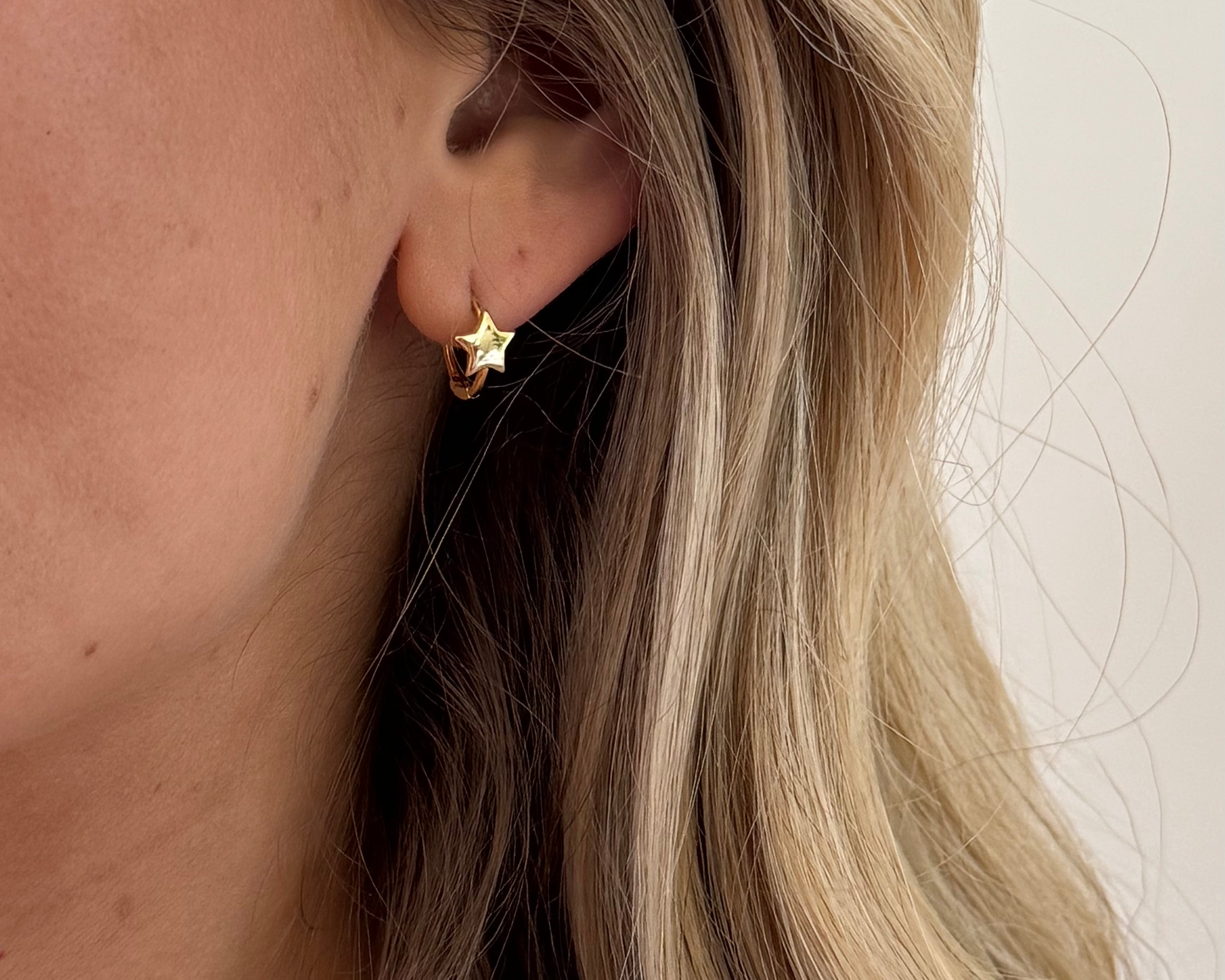 Close-up of a person wearing a gold star-shaped earring with blonde hair.