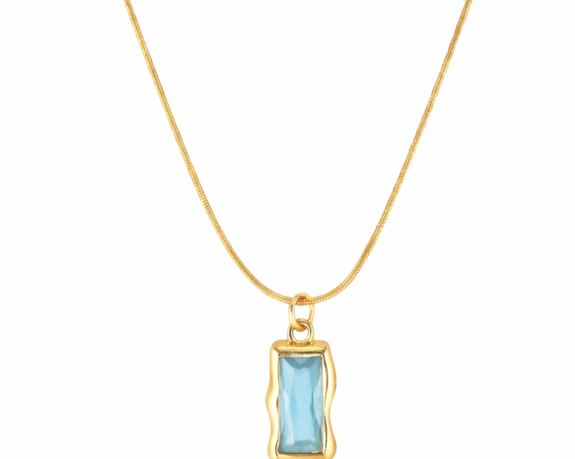 Gold necklace with a blue gemstone pendant on a white background