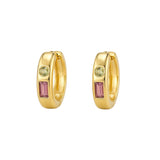 A pair of gold huggie hoop earrings with a rectangular pink gemstone and a round light green gemstone on each earring, set against a light gray background.