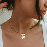 Gold necklace with a cherry pendant worn by a person