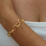 Gold chain bracelet on a wrist with a blurred background