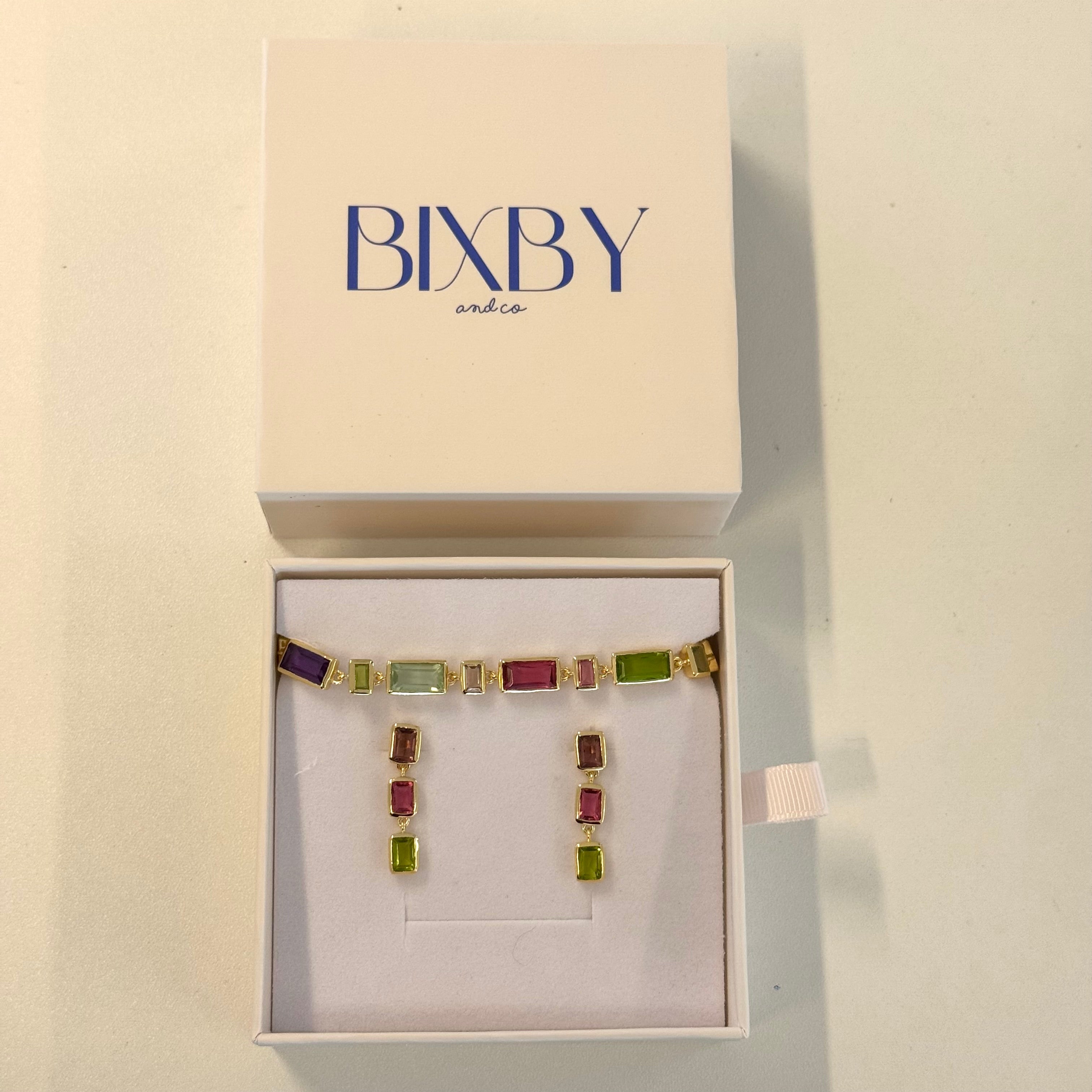 Multicolored gemstone earrings in a Bixby box on a beige background