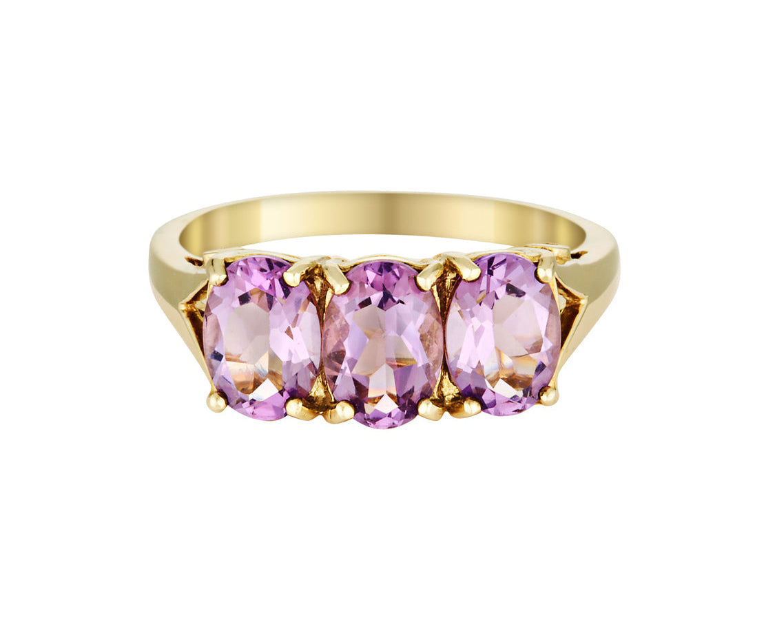 Gold ring with three pink gemstones on a white background