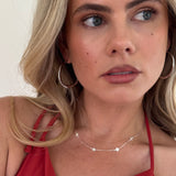 Woman wearing a red top and silver hoop earrings with a neutral background