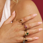 Close-up of a hand wearing multiple rings with gemstones on a blurred background