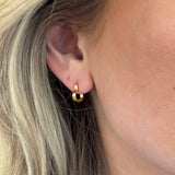 Close-up of a person wearing a gold earring with blonde hair.