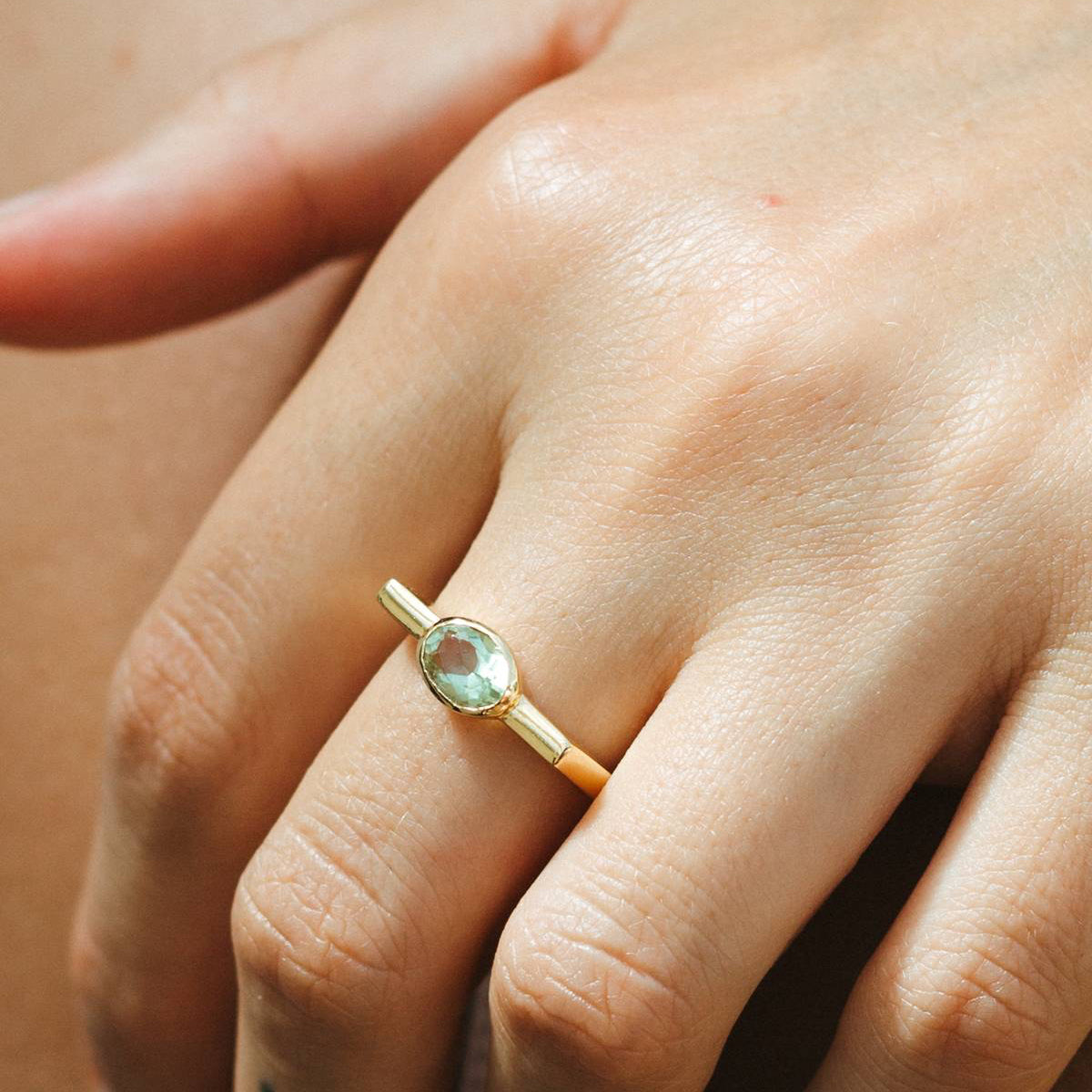 Gold ring with a green gemstone on a person's finger