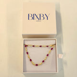 Gold and red beaded necklace in a Bixby box on a beige background