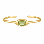 A gold open cuff bracelet featuring a central square-cut light green gemstone, with the brand name 'BIXBY' engraved on the inside, shown against a plain white background.
