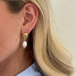 Close-up of a person wearing a pearl earring with a gold setting.