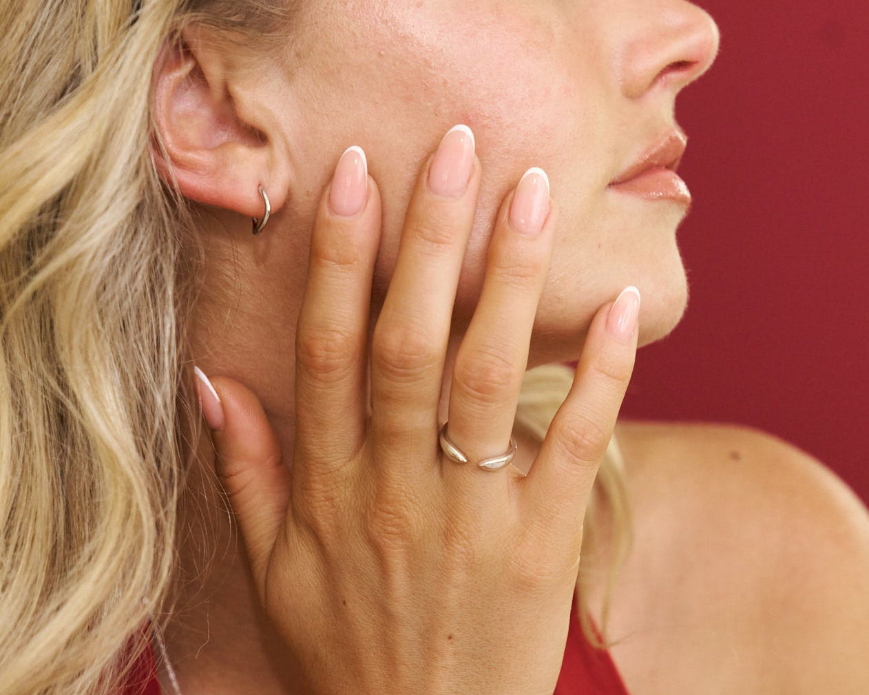 Woman in a red dress with a ring on her finger against a red background