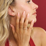 Woman in a red dress with a ring on her finger against a red background