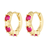 Gold hoop earrings with red gemstones on a white background