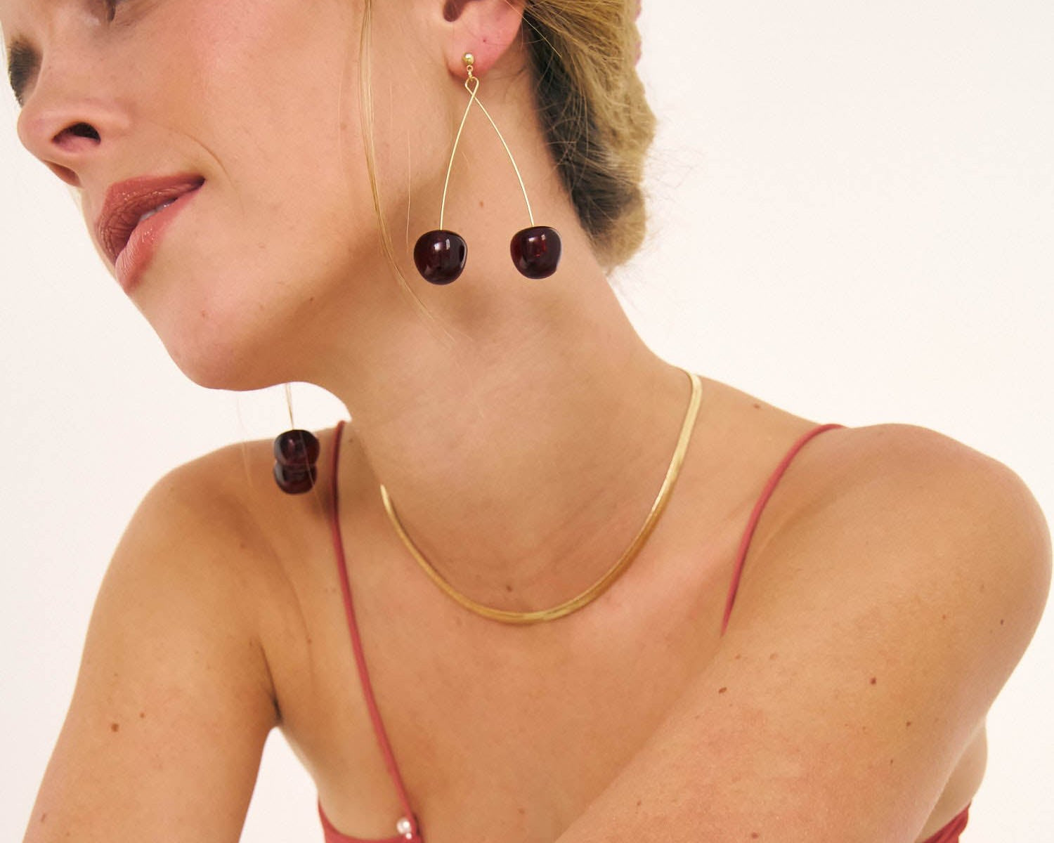 Model in red dress and Bixby and Co cherry shape earrings
