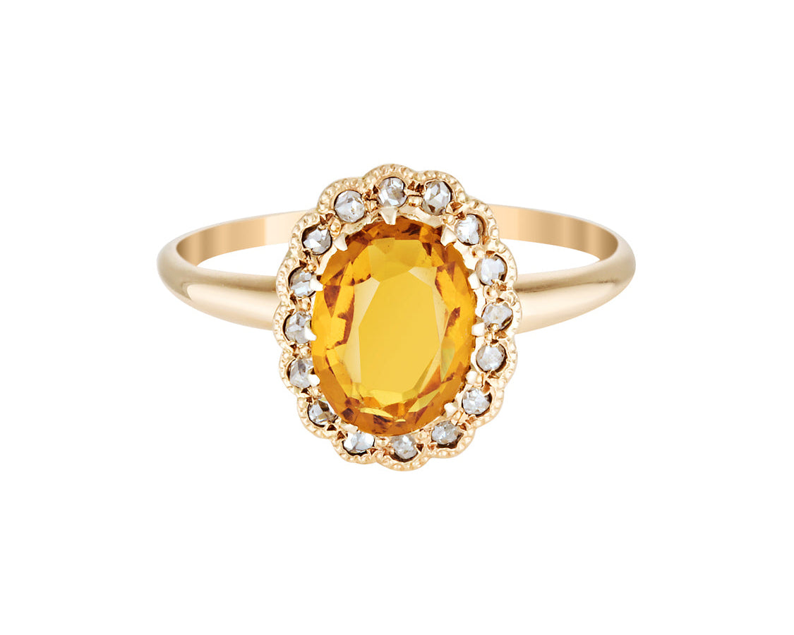 Gold ring with a yellow gemstone on a white background