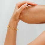 Gold bracelet on a wrist with a neutral background
