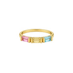A gold ring featuring three rectangular baguette-cut gemstones in pink, yellow, and light blue, set against a plain light gray background.