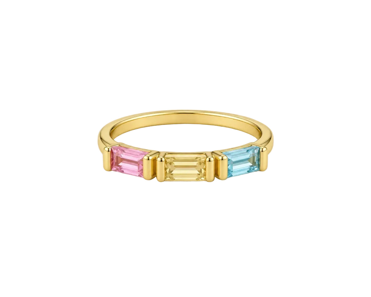 A gold ring featuring three rectangular baguette-cut gemstones in pink, yellow, and light blue, set against a plain light gray background.