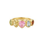 A gold ring featuring five heart-shaped gemstones in different colors: light green, pale yellow, pink, light blue, and dark red, set in a polished gold band on a light beige background.