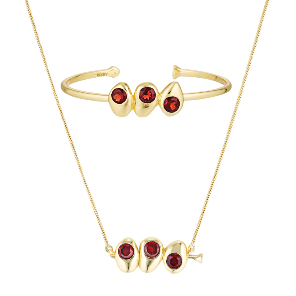 Gold bracelet and necklace set with red gemstones on a white background