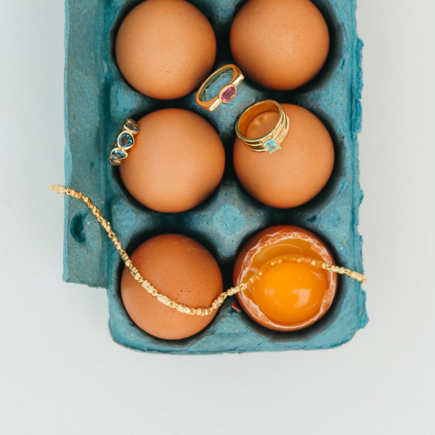 Eggs in a carton with jewelry items on top