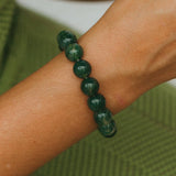 Green beaded bracelet on a wrist with a blurred green background