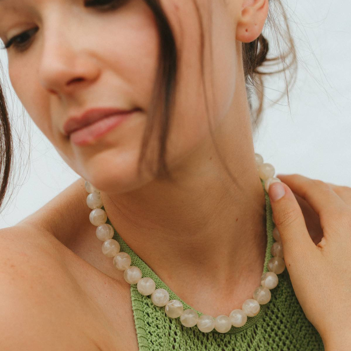 Woman wearing a beaded necklace and bracelet against a blurred background