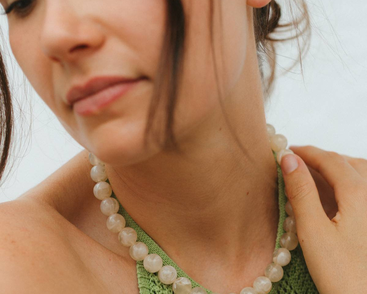 Woman wearing a beaded necklace and bracelet against a blurred background