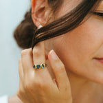 Close-up of a woman wearing a blue ring and earring, with a blurred background