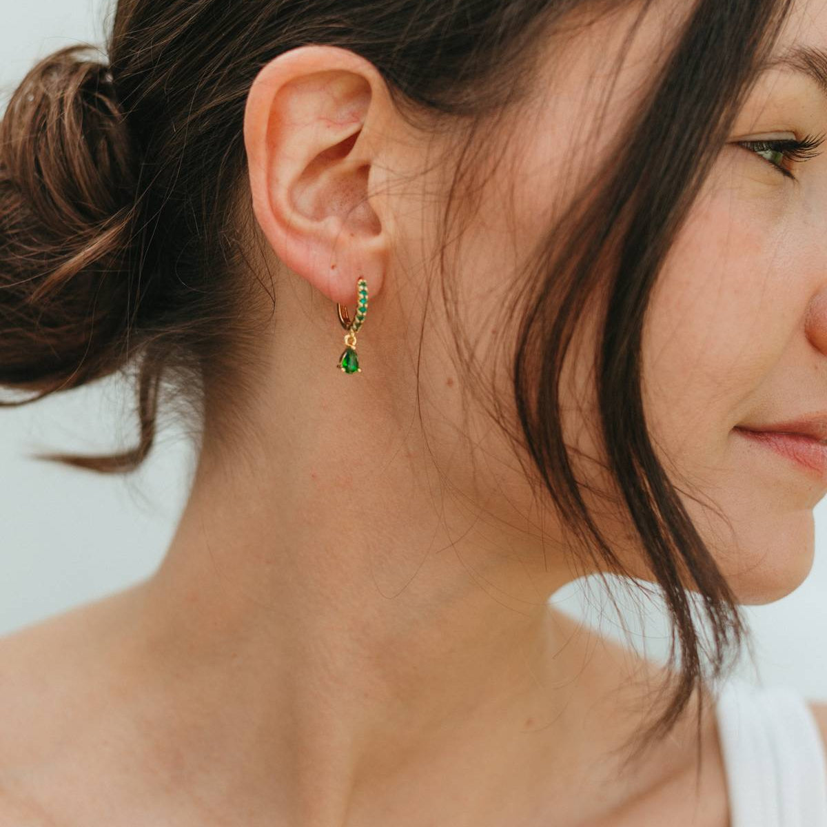 Close-up of a woman wearing green earrings with a blurred background