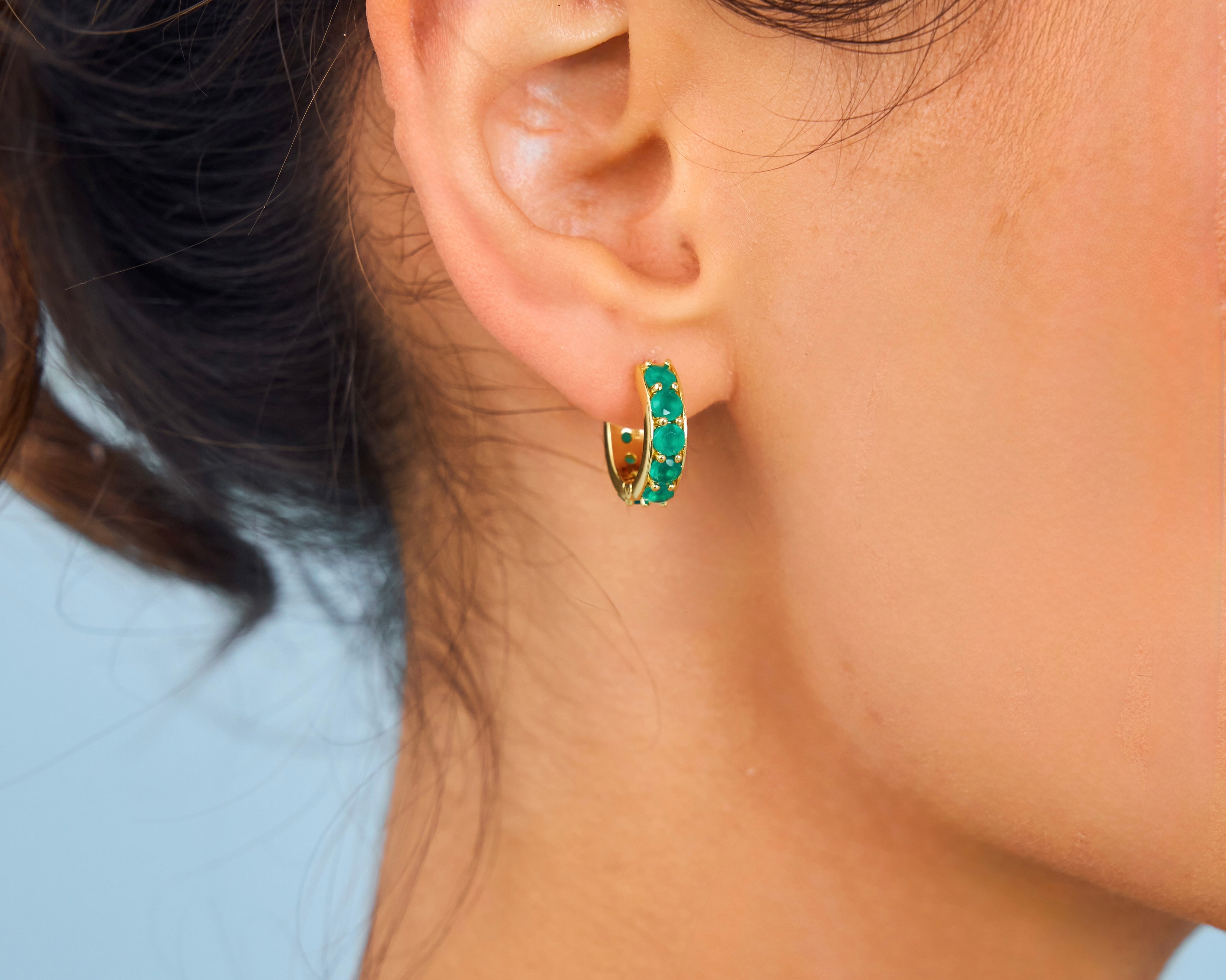 Model wearing green gemstone hoops 