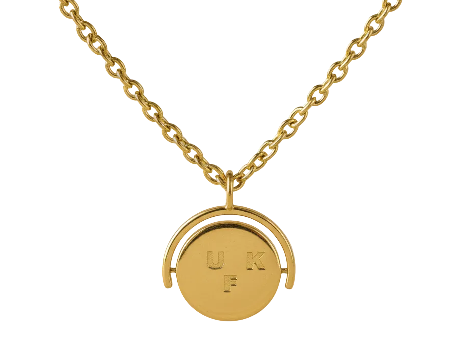 Gold necklace with a round pendant on a beige background