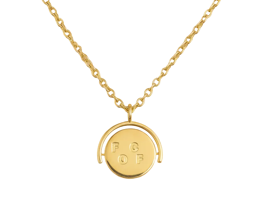 Gold necklace with a round pendant on a beige background