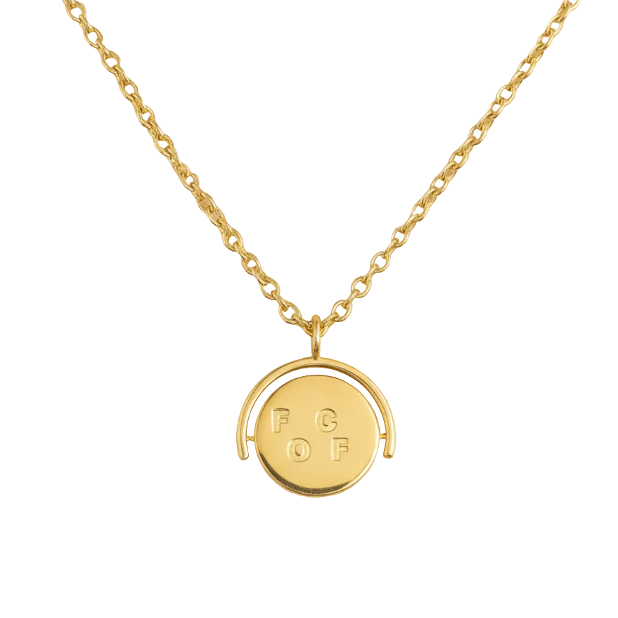 Gold necklace with a round pendant on a beige background