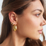 Model wearing large bold square shaped gold hoops 
