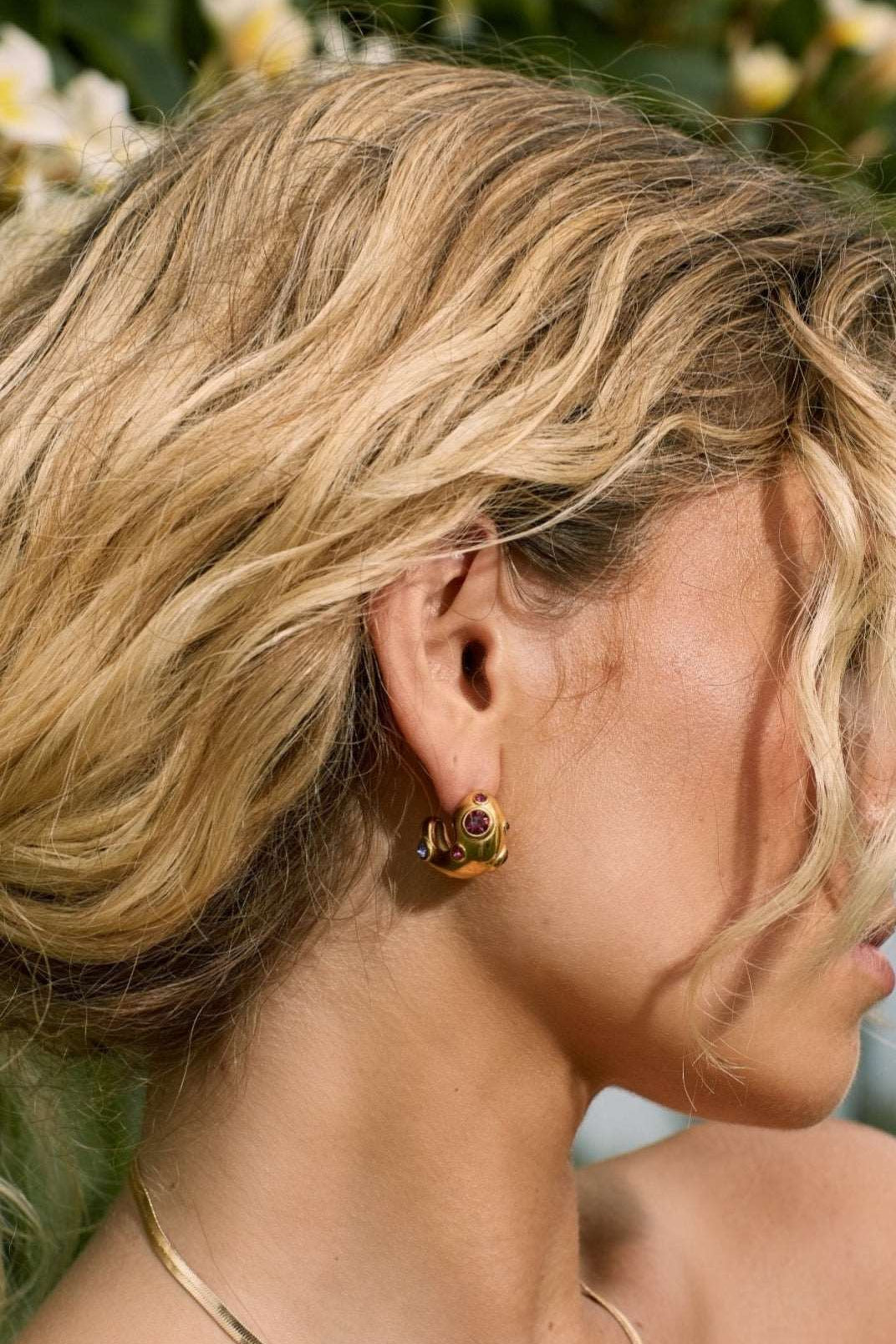 Pink and purple coloured gemstone earrings on blonde girl